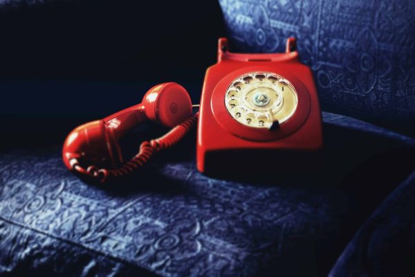 Red Rotary Telephone On Blue Sofa